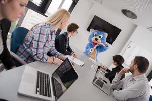 boss dresed as bear having fun with business people in trendy office photo