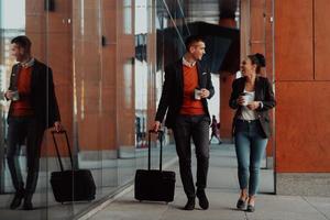 hombre de negocios y mujer de negocios hablando y sosteniendo equipaje viajando en un viaje de negocios, llevando café recién hecho en sus manos.concepto de negocio foto