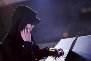 talented hacker using laptop computer while working in dark office photo