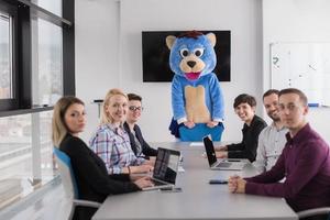 boss dresed as bear having fun with business people in trendy office photo