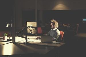 man working on computer in dark office photo