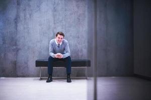 hombre de negocios que usa un teléfono inteligente mientras está sentado en el banco foto