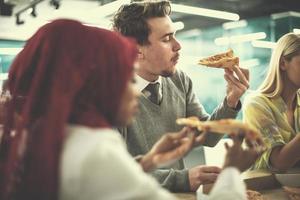equipo de negocios multiétnico comiendo pizza foto