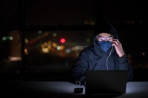 hacker using laptop computer while working in dark office photo