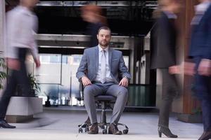 business man sitting in office chair, people group  passing by photo