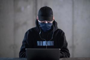 talented hacker using laptop computer while working in dark office photo
