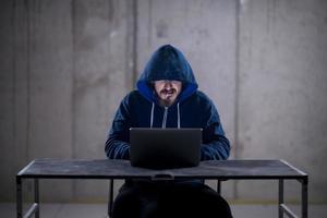 young hacker using laptop computer while working in dark office photo