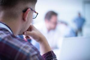 Business man writing notes while working on laptop photo
