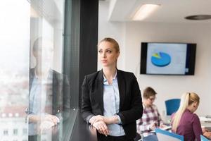 retrato de una joven mujer de negocios en la oficina con un equipo en una reunión en segundo plano foto