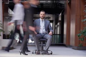 business man sitting in office chair, people group  passing by photo