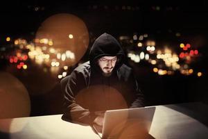 hacker using laptop computer while working in dark office photo