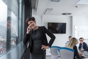 Elegant Woman Using Mobile Phone by window in office building photo