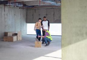 worker using laptop computer while showing house design plans photo
