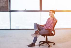 joven empresario casual usando teléfono móvil en el sitio de construcción foto