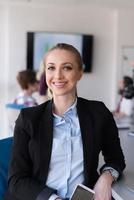 portrait of young business woman at office with team on meeting in background photo