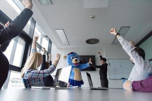 boss dresed as bear having fun with business people in trendy office photo