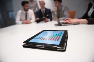 close up of touchpad with analytics documents at business meeting photo