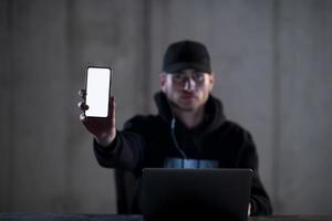 criminal hacker using laptop computer while working in dark office photo