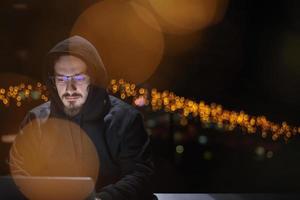 hacker using laptop computer while working in dark office photo