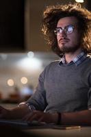 man working on computer in dark office photo