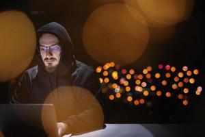 hacker using laptop computer while working in dark office photo