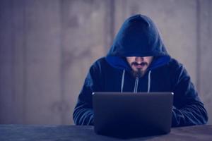 talented hacker using laptop computer while working in dark office photo