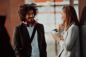 Two serious businessmen drinking coffee to take away. Man and middle-aged woman in official shirt standing outside. Coffee break concept photo