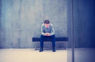 hombre de negocios que usa un teléfono inteligente mientras está sentado en el banco foto