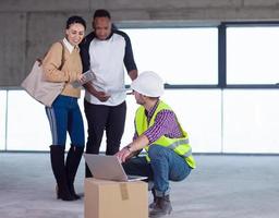 worker using laptop computer while showing house design plans photo