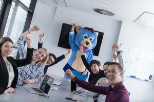 boss dresed as bear having fun with business people in trendy office photo