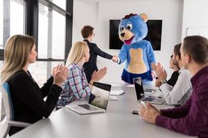 boss dresed as bear having fun with business people in trendy office photo