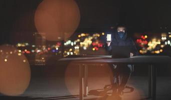 hacker using laptop computer while working in dark office photo