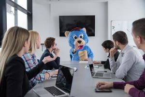 jefe vestido como oso divirtiéndose con gente de negocios en una oficina de moda foto