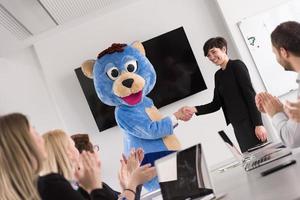 jefe vestido como oso divirtiéndose con gente de negocios en una oficina de moda foto