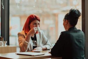 Two young business women sitting at table in cafe.Girl using laptop, smartphone, blogging. Teamwork, business meeting. Freelancers working... photo