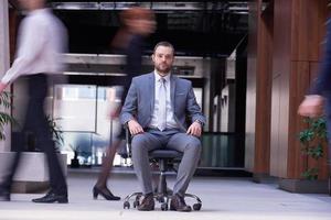 business man sitting in office chair, people group  passing by photo