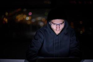 hacker using laptop computer while working in dark office photo