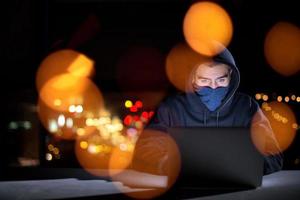 hacker using laptop computer while working in dark office photo