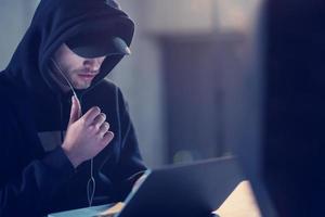 talented hacker using laptop computer while working in dark office photo