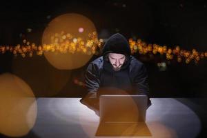 hacker using laptop computer while working in dark office photo