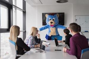 jefe vestido como oso divirtiéndose con gente de negocios en una oficina de moda foto