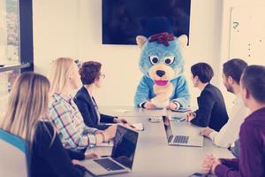 boss dresed as bear having fun with business people in trendy office photo