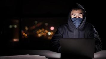 hacker using laptop computer while working in dark office photo