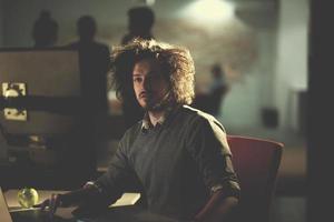 man working on computer in dark office photo