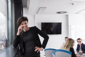 Elegant Woman Using Mobile Phone by window in office building photo