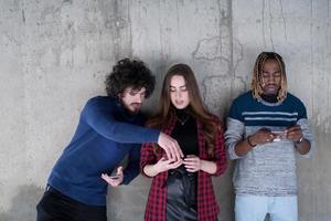 casual multiethnic business team using mobile phones in front of a concrete wall photo