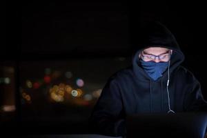 hacker using laptop computer while working in dark office photo