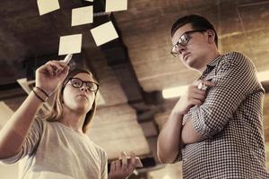 young couple at modern office interior writing notes on stickers photo