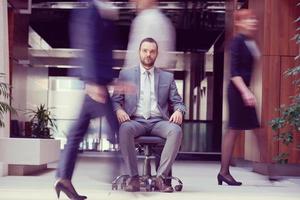 business man sitting in office chair, people group  passing by photo