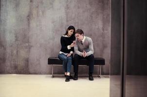 business couple using mobile phone while sitting on the bench photo